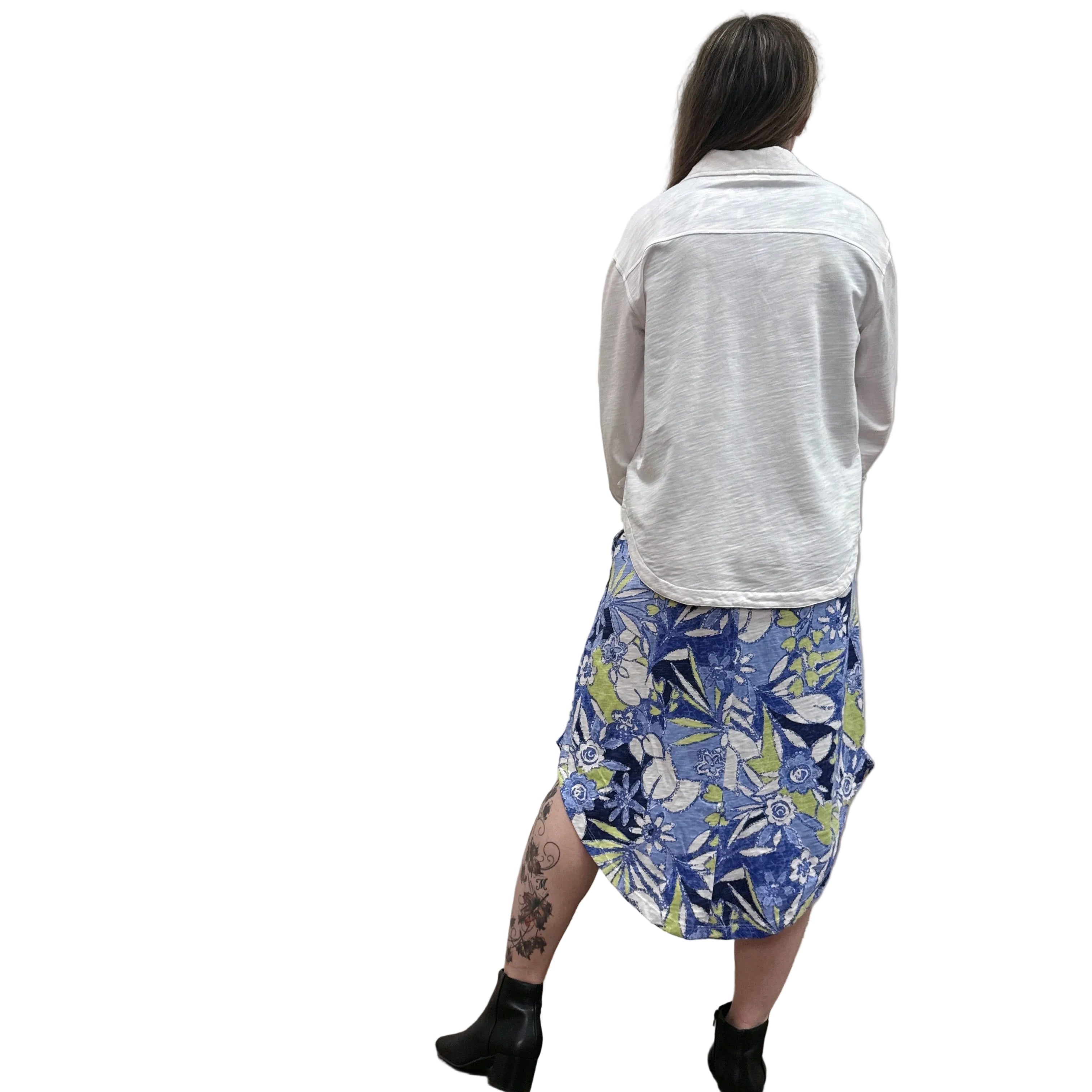 Person wearing a white Papa Anywhere Shacket shirt and blue floral dress standing against a plain wall.