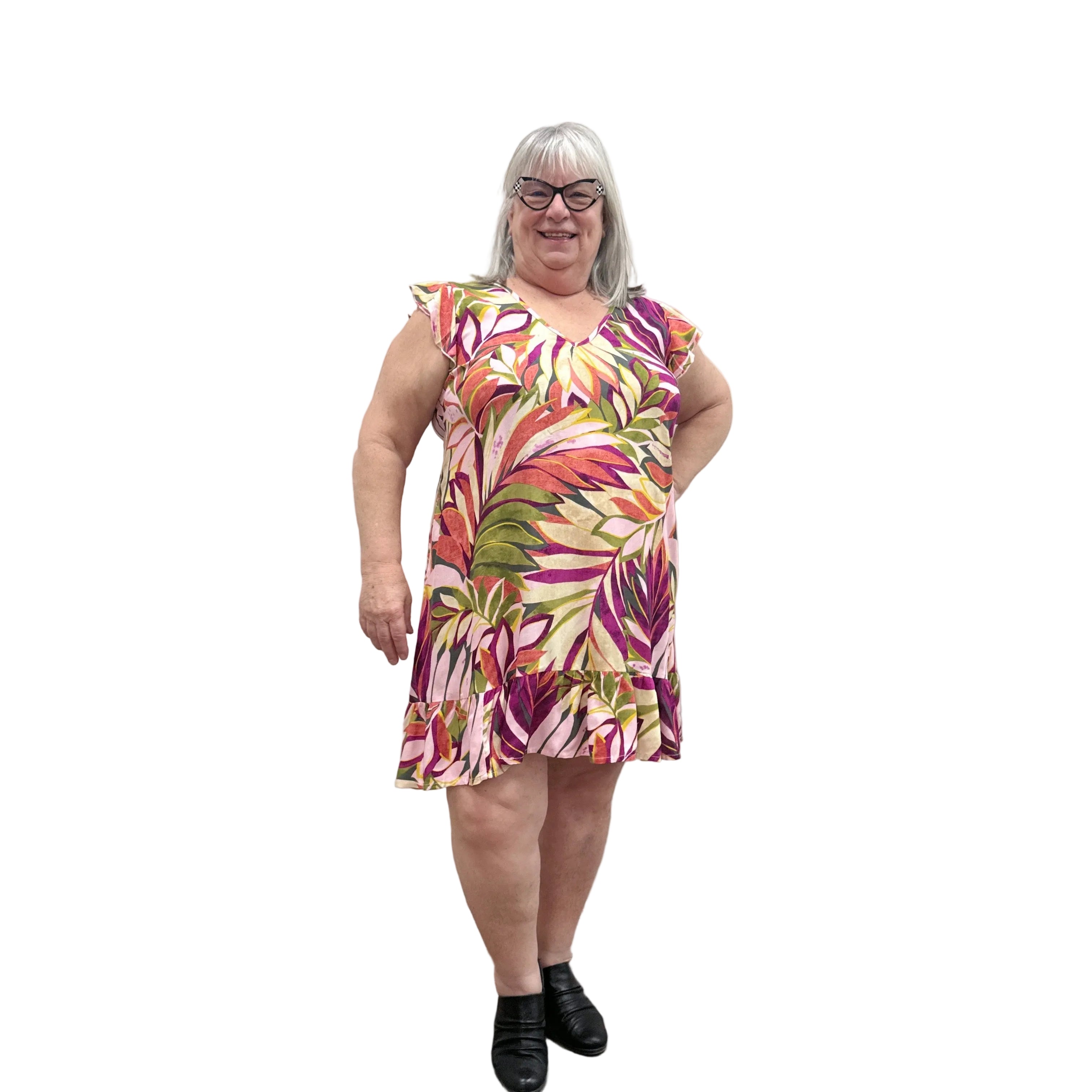 Woman wearing a colorful floral Papa Classic Print dress in Pink against a plain wall.