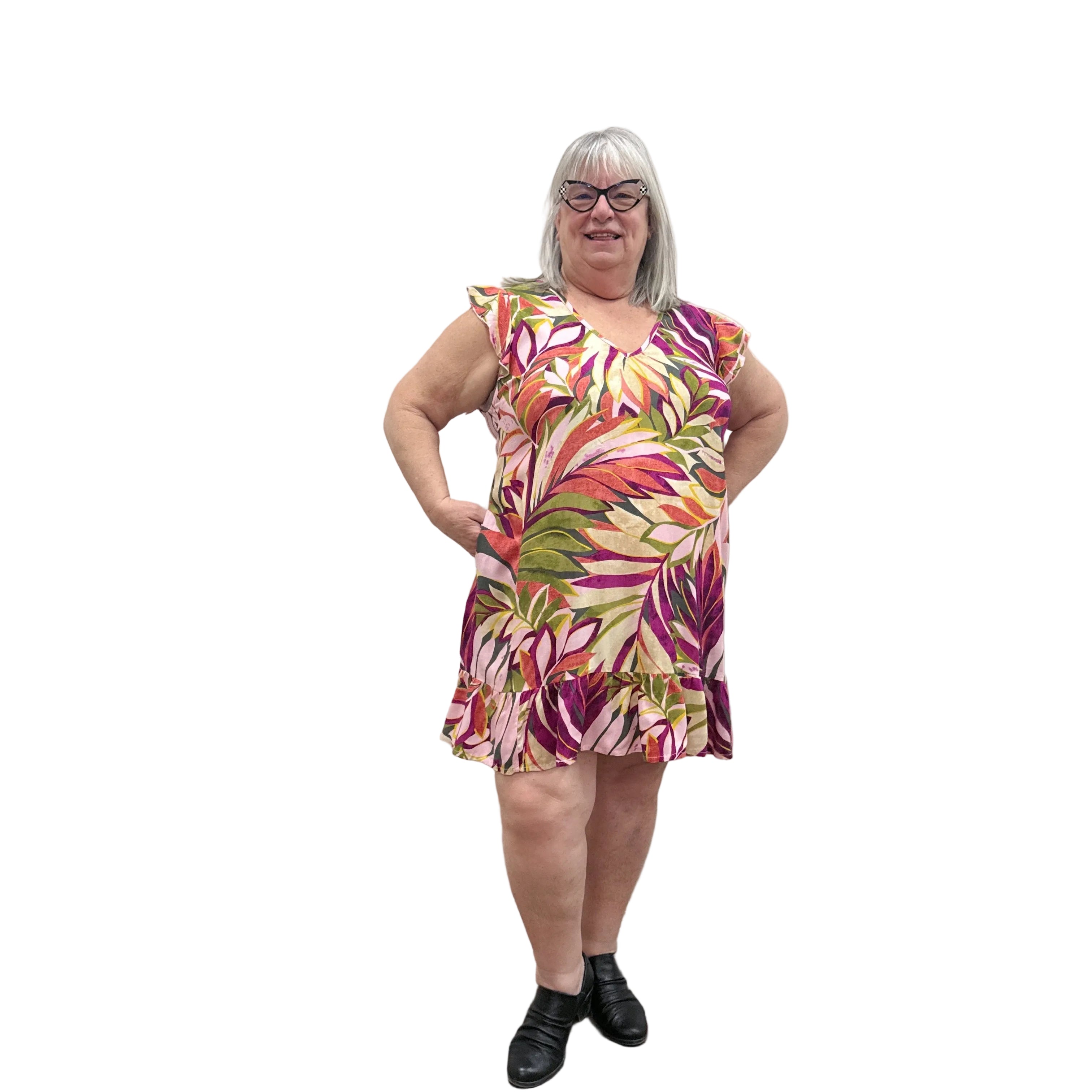Woman wearing a colorful floral Papa Classic Print dress in Pink against a plain wall.