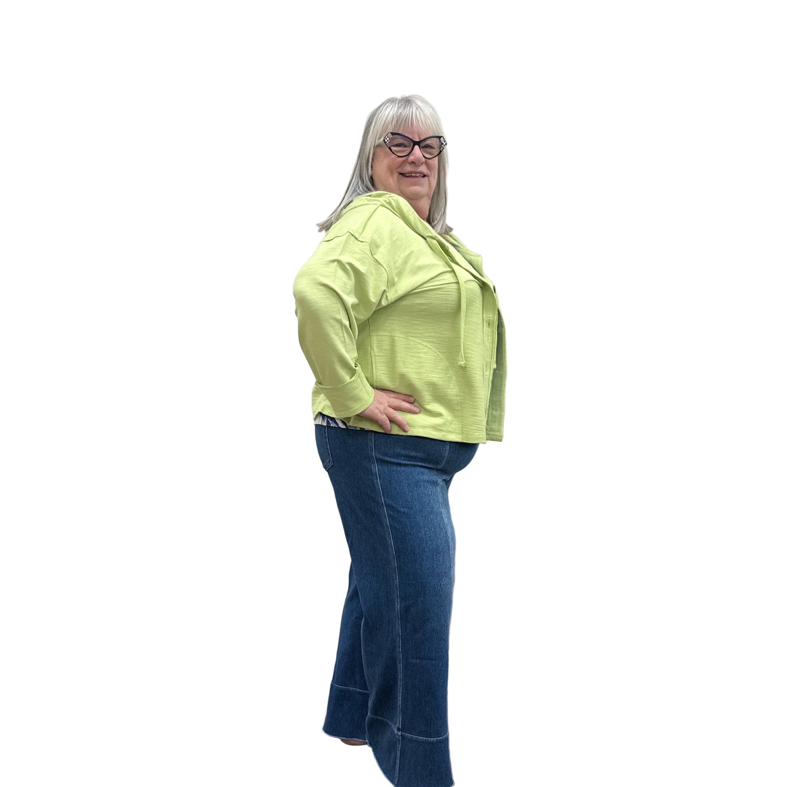 Person wearing a kiwi green Cruising Hoodie jacket and blue pants standing against a plain wall.