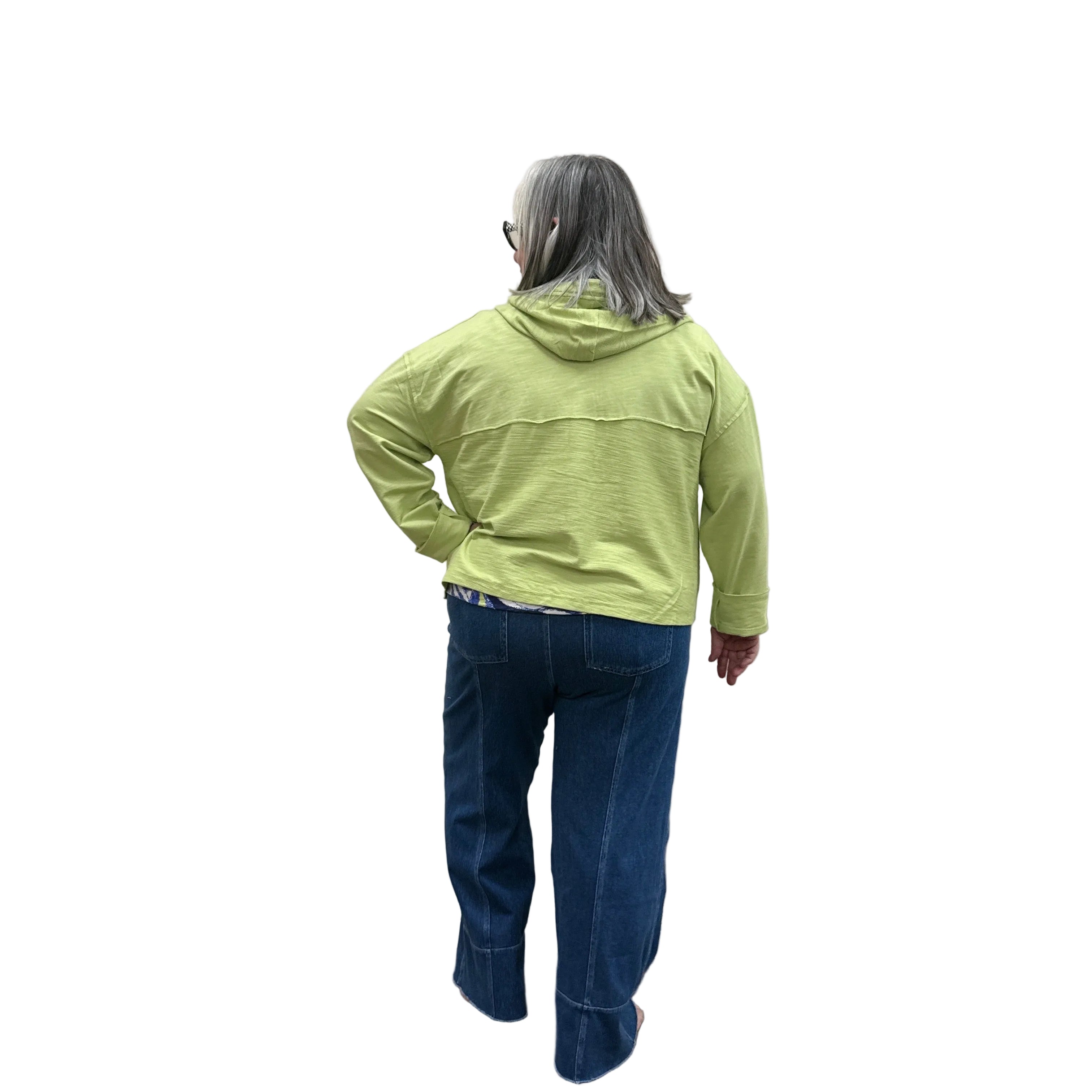 Person wearing a kiwi green Cruising Hoodie jacket and blue pants standing against a plain wall.