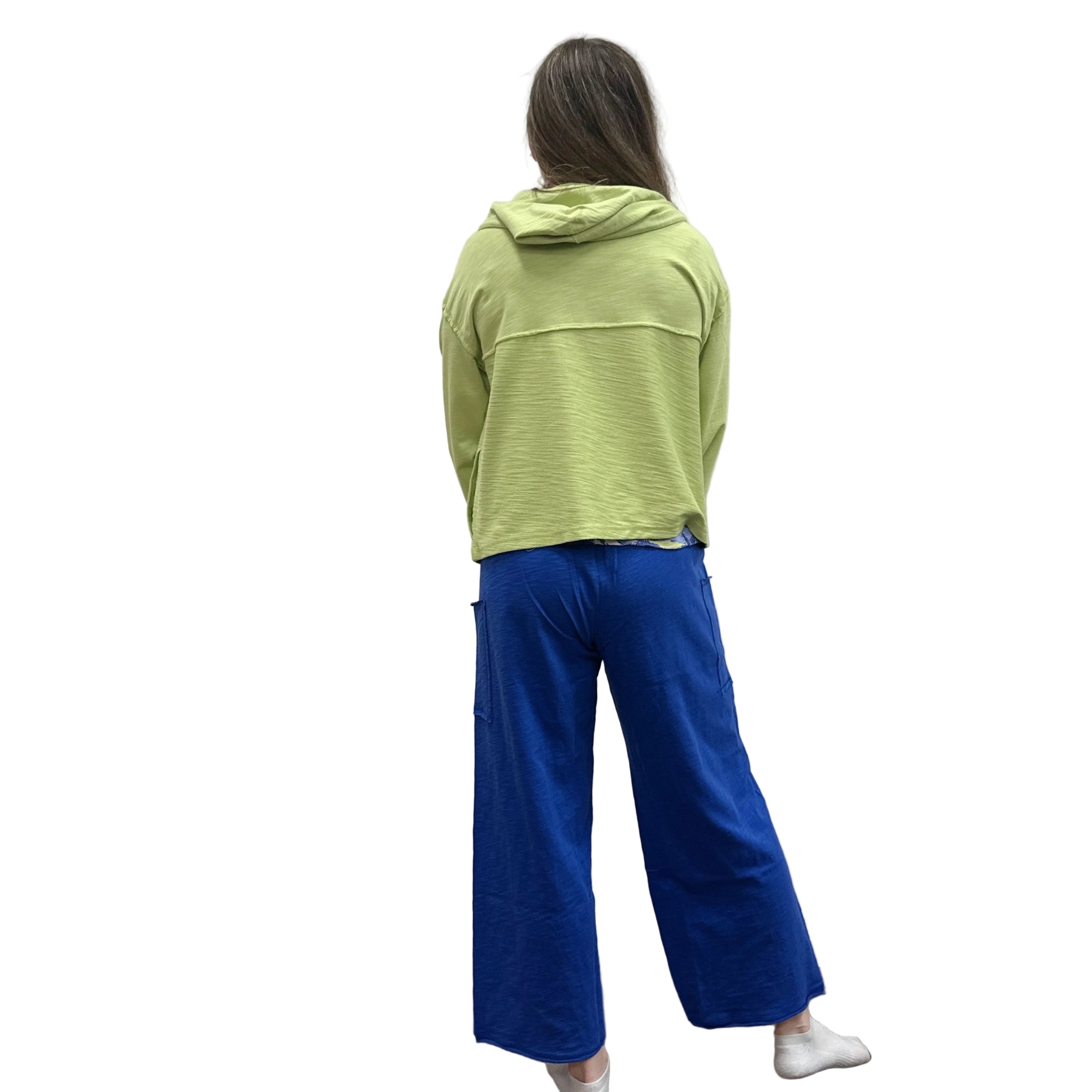 Person wearing a kiwi green Cruising Hoodie jacket and blue pants standing against a plain wall.
