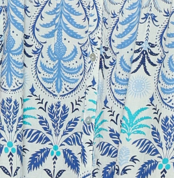 Woman wearing a sleeveless dress with a blue floral pattern on a white background