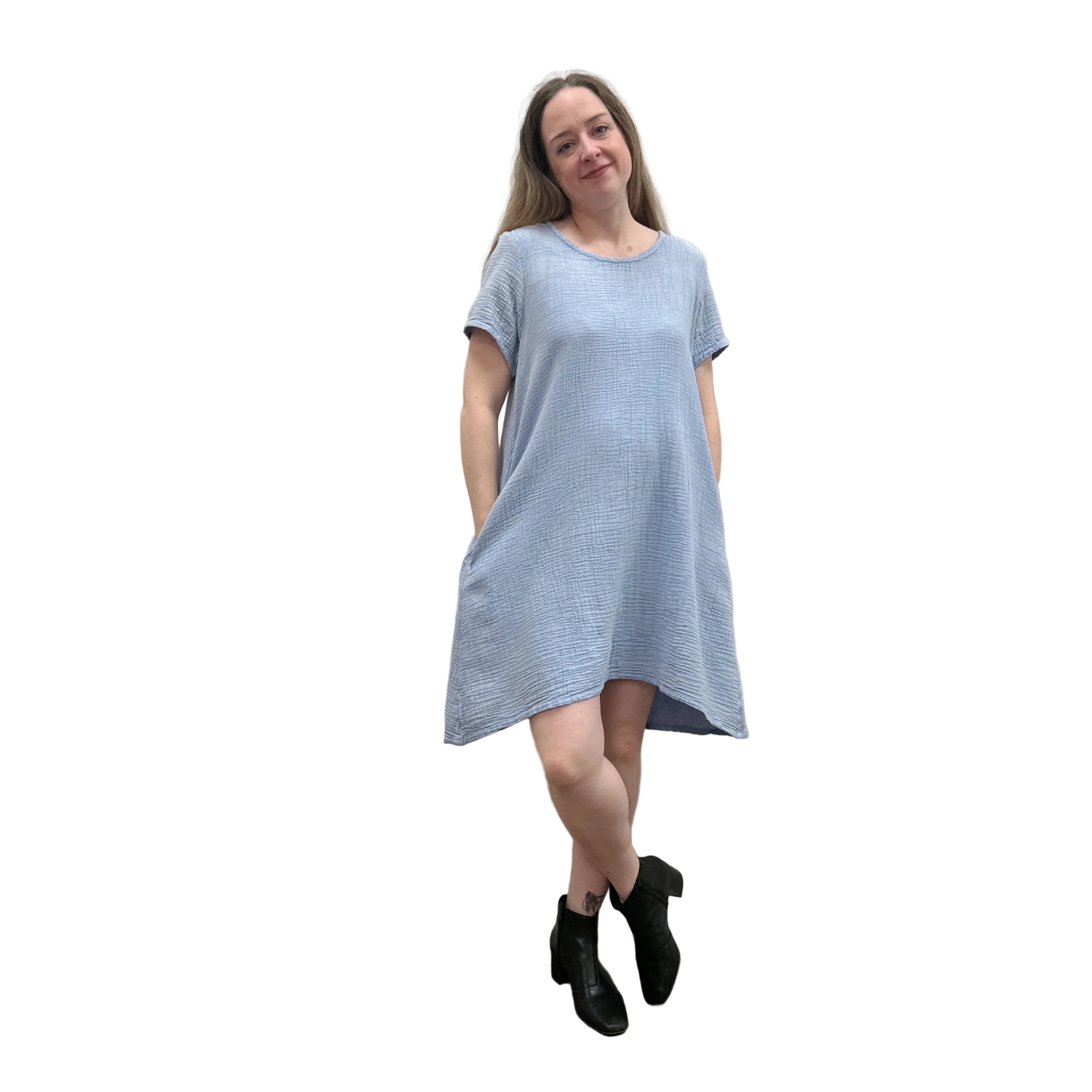Woman wearing a light blue Papa Passport dress against a plain wall.