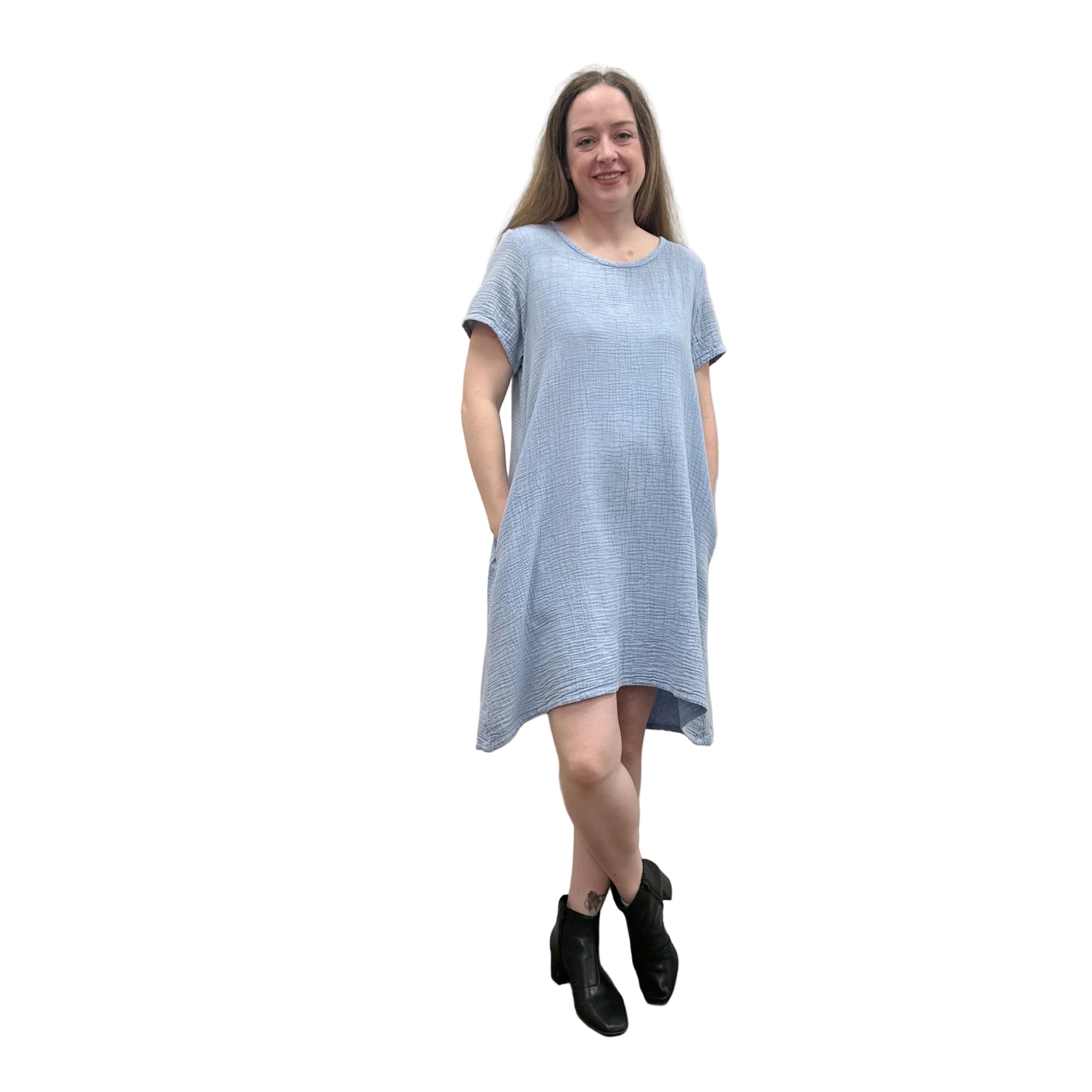 Woman wearing a light blue Papa Passport dress against a plain wall.