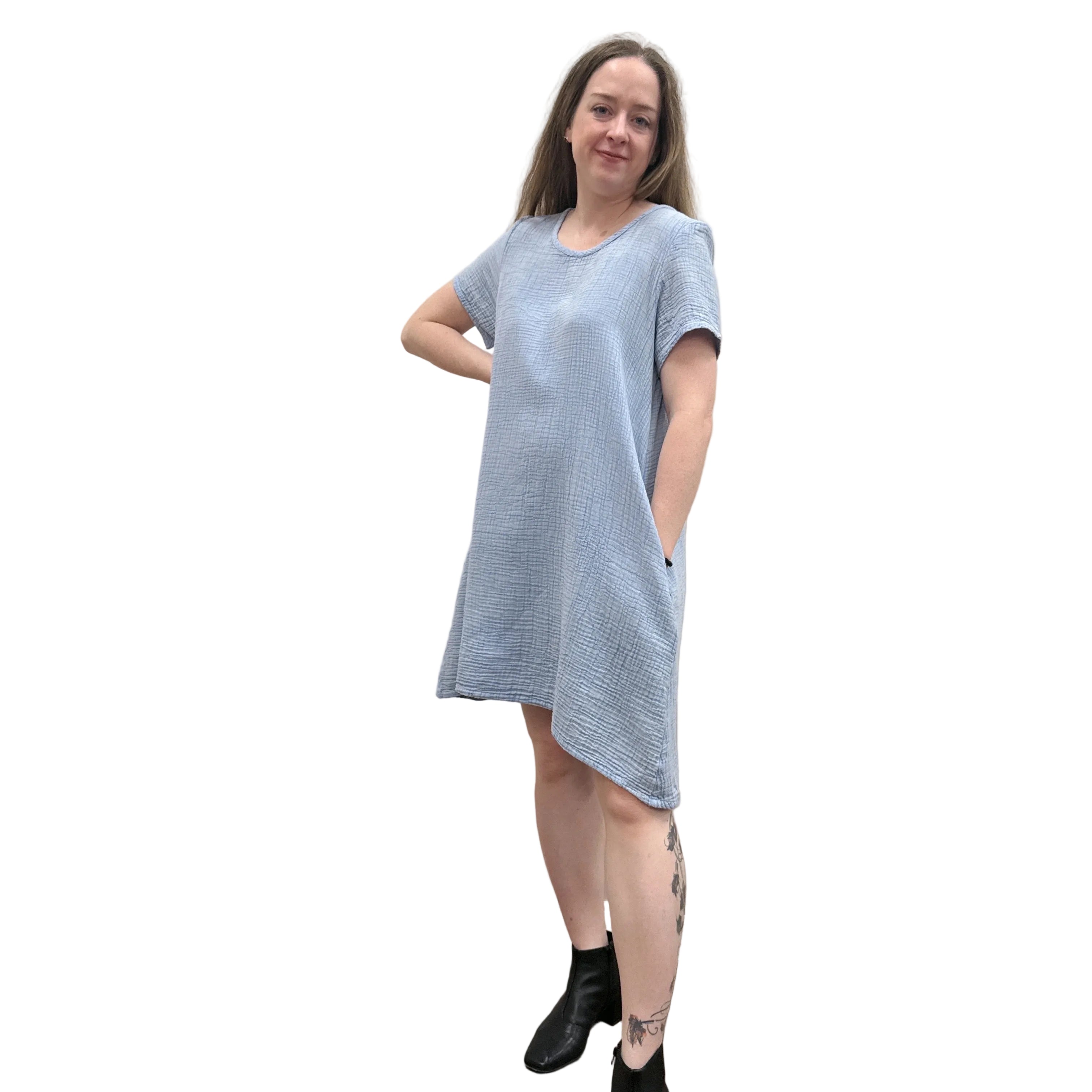 Woman wearing a light blue Papa Passport dress against a plain wall.