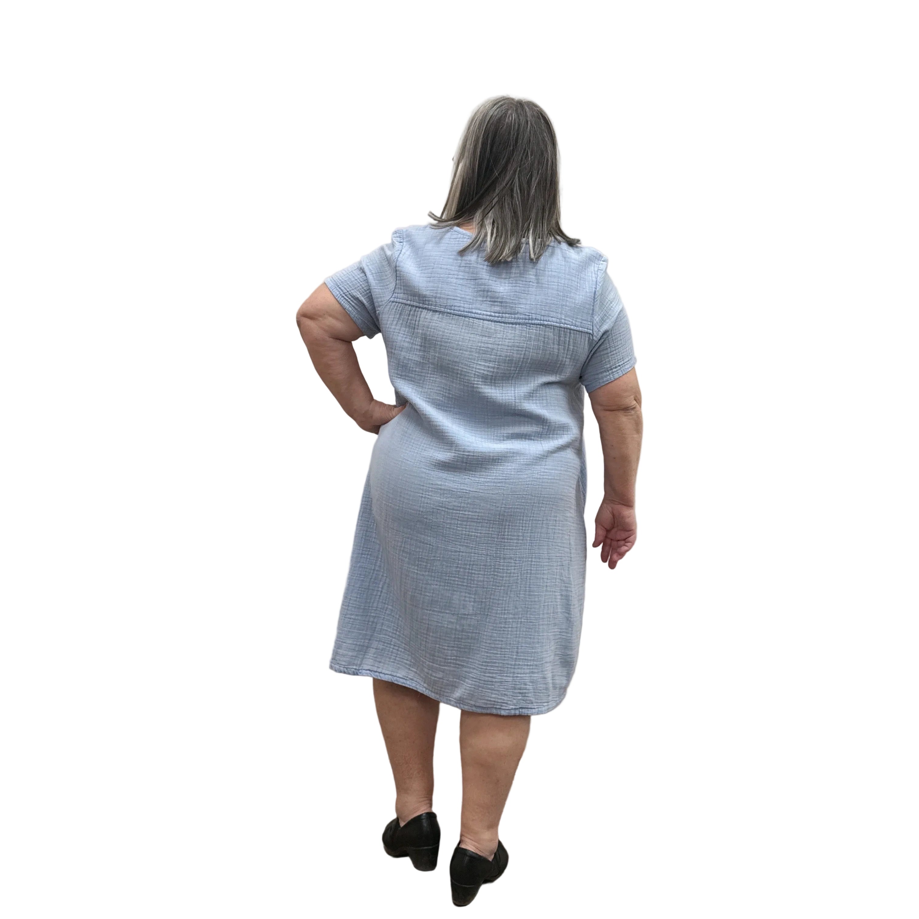 Woman wearing a light blue Papa Passport dress against a plain wall.
