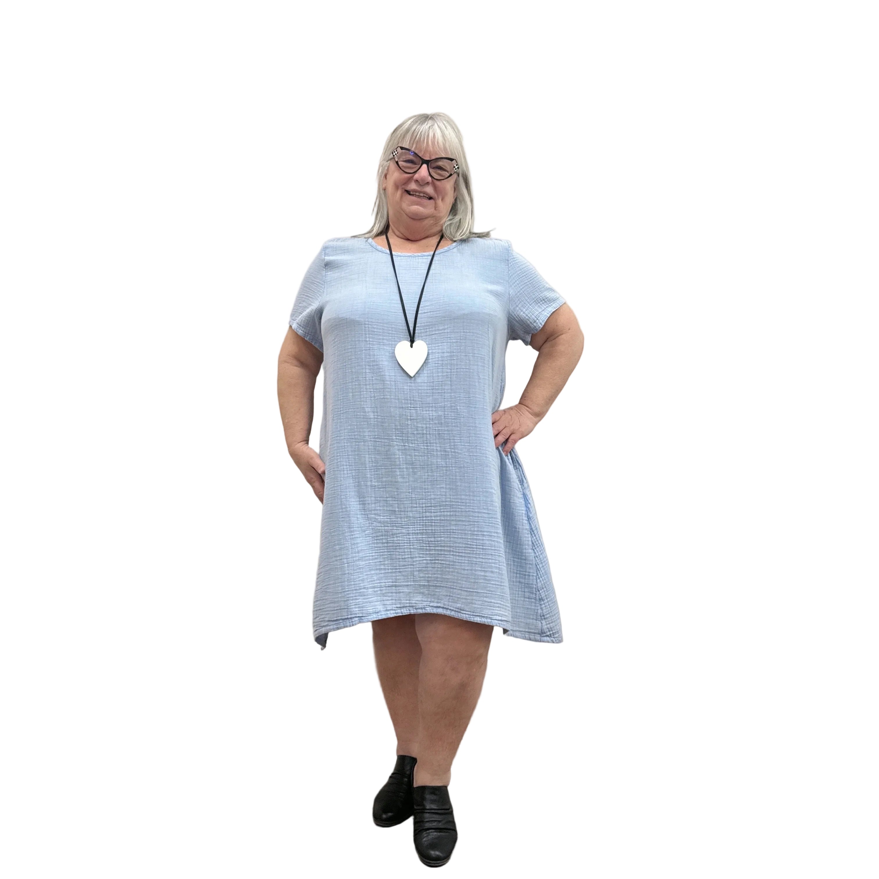 Woman wearing a light blue Papa Passport dress against a plain wall.