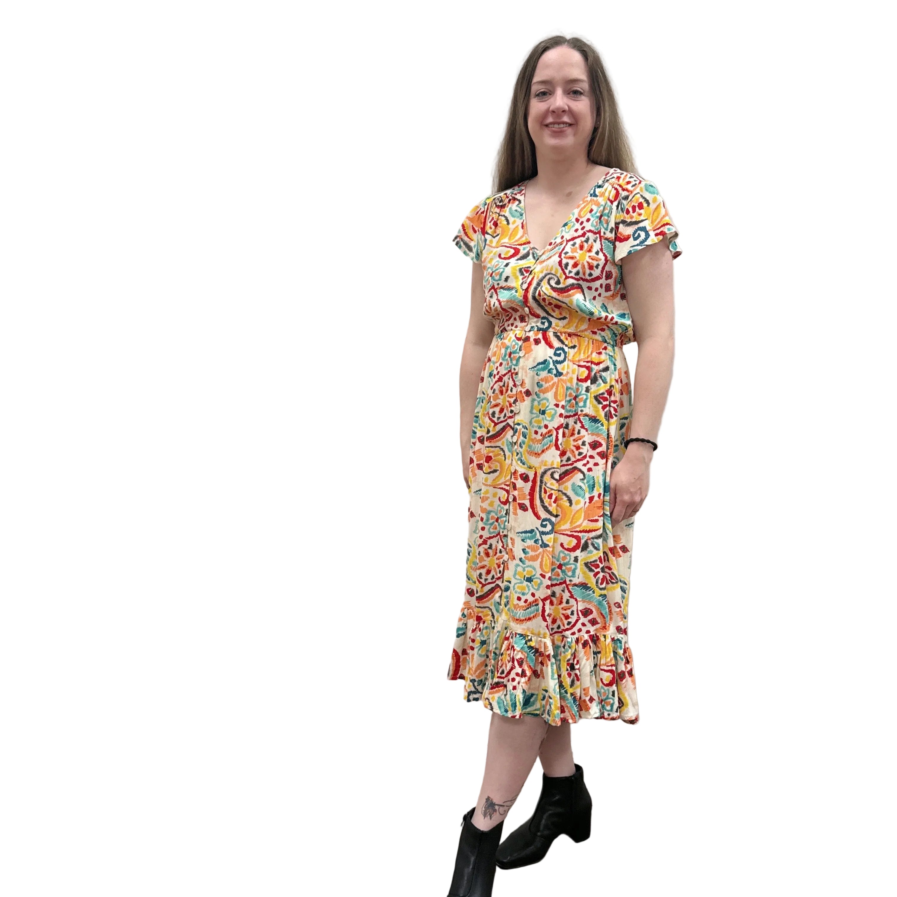 Woman wearing a colorful patterned Papa Saffron Bloom Midi dress against a plain wall.