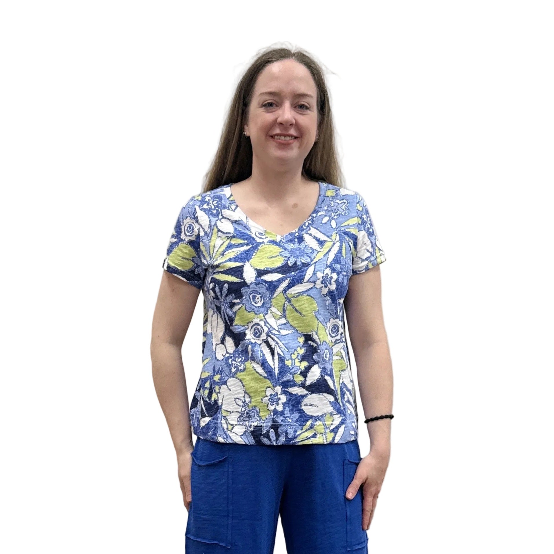 Person wearing a blue floral Papa V Neck top and blue pants standing against a plain wall.