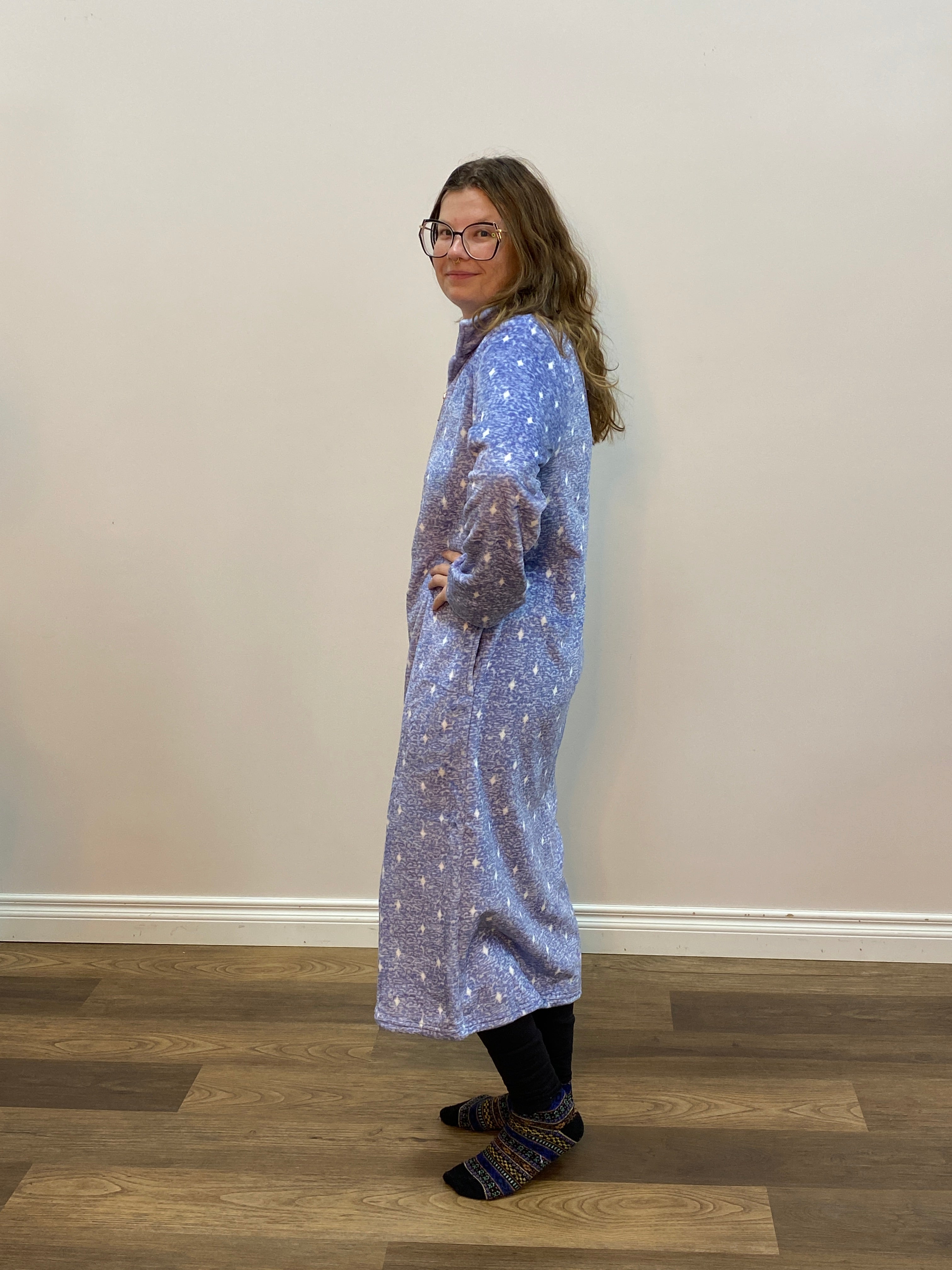 Person wearing a long, light blue robe with a pattern, standing indoors.
