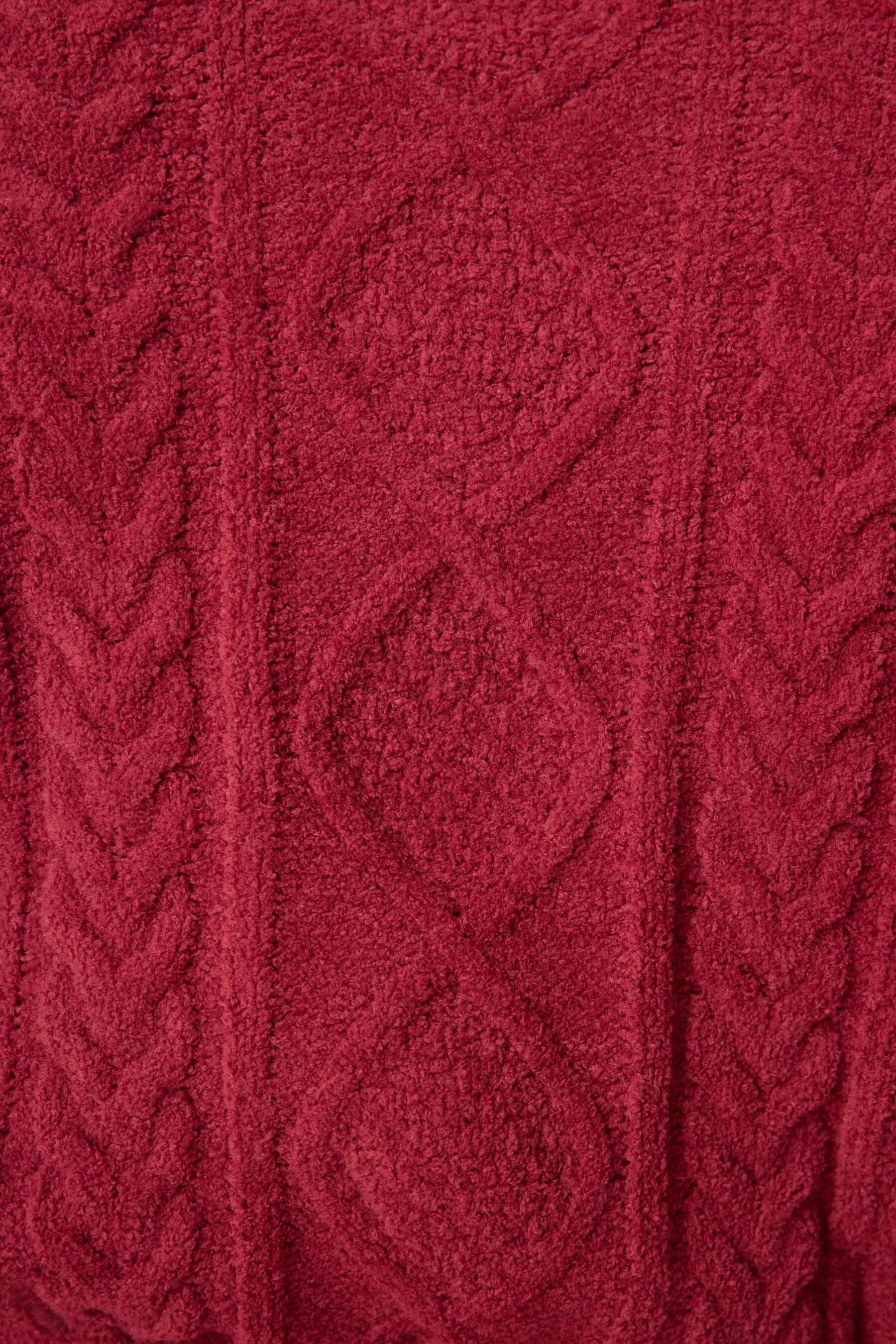 Close-up of a red knitted fabric with cable pattern
