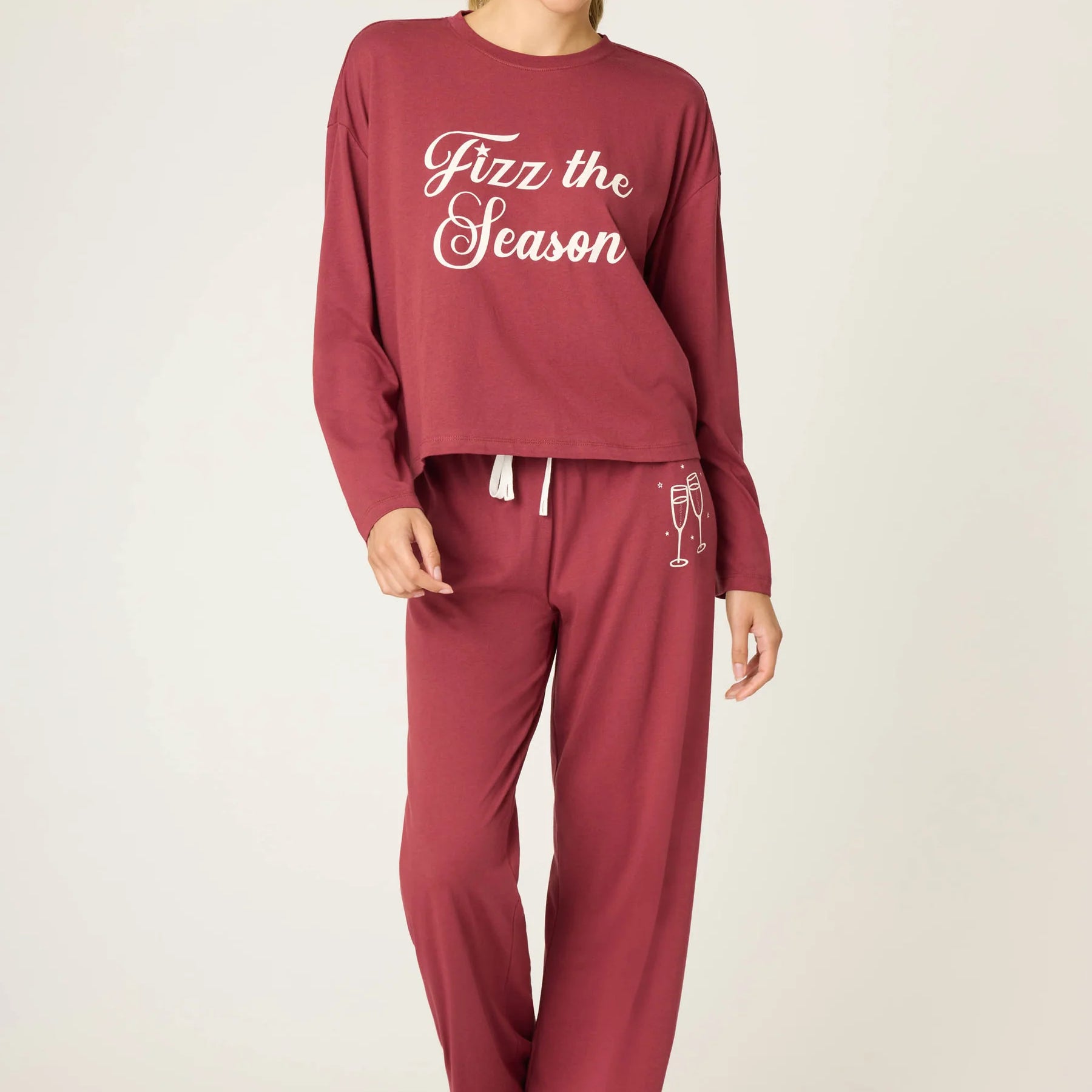 Woman wearing a burgundy pajama set with 'Fizz the Season' text on a white background