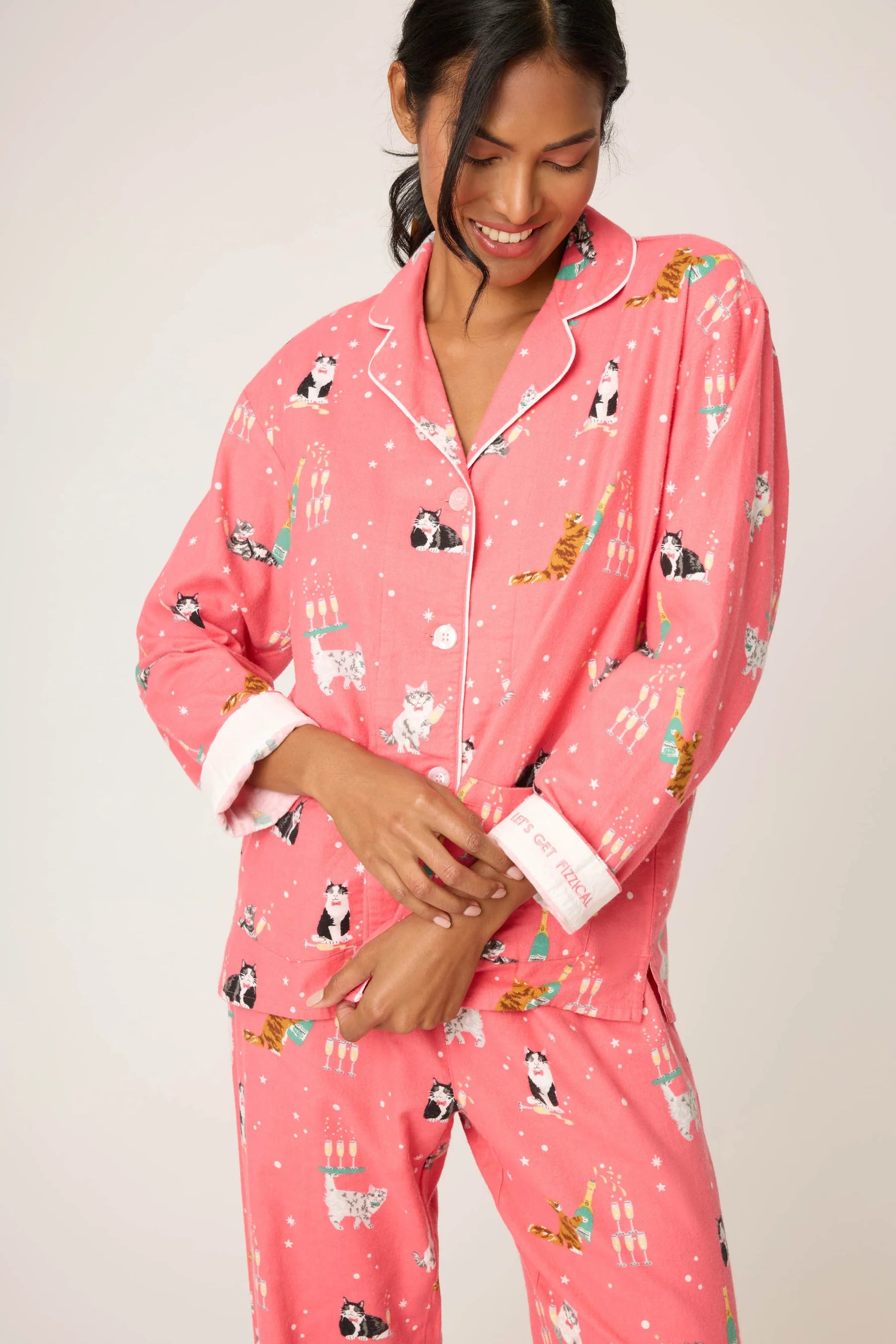 Woman wearing pink pajamas with animal prints on a plain background