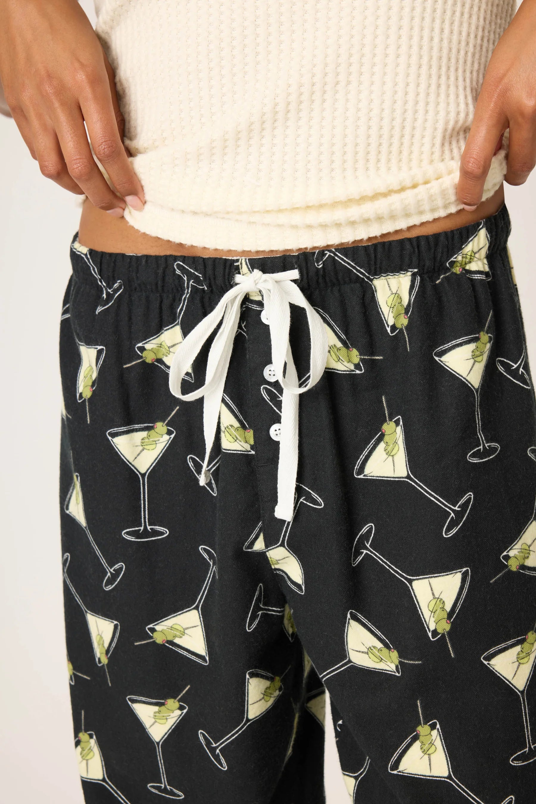 Black pajama pants with martini glass pattern worn by a person.