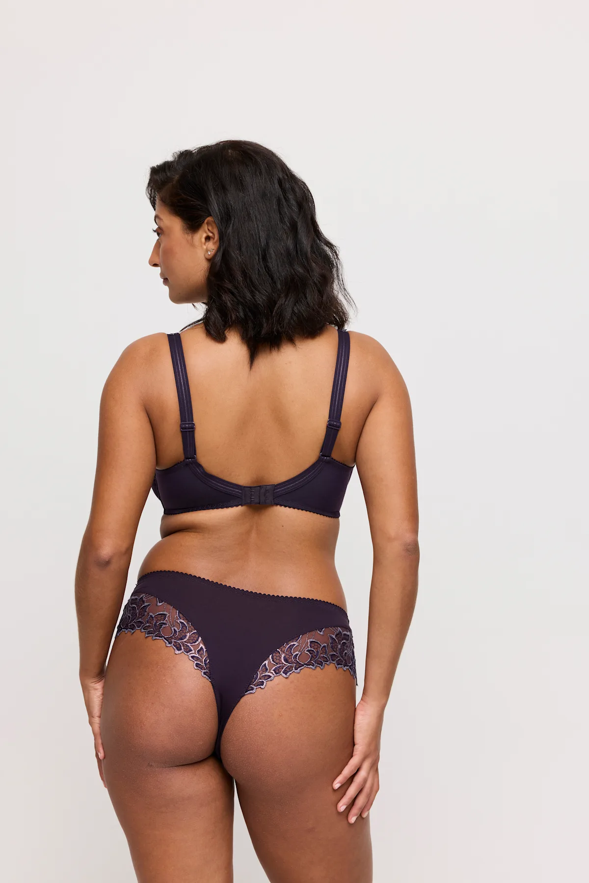 Woman wearing a dark purple lingerie set on a white background