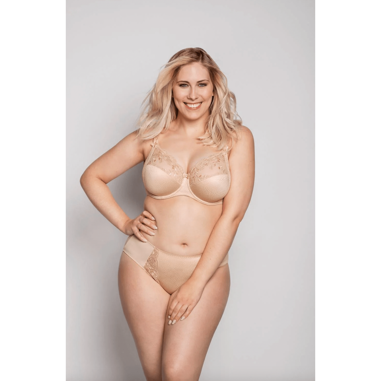 A woman wearing a beige underwire full cup bra with embroidery detailing.