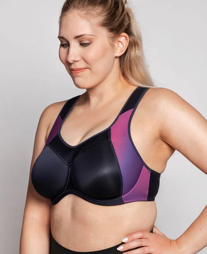 Woman wearing a black and purple sports bra against a plain background