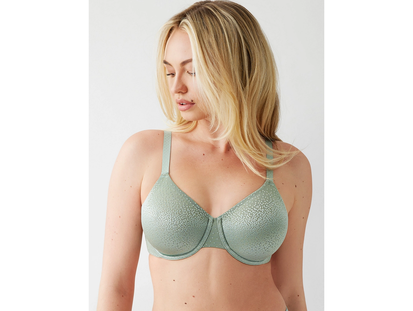 Woman wearing a green bra against a white background