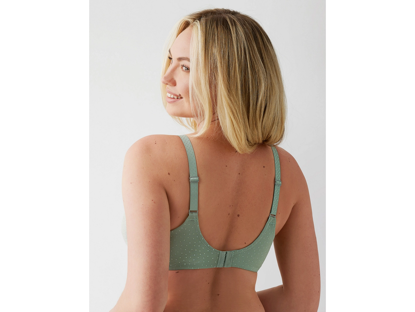Woman wearing a green bra against a plain background