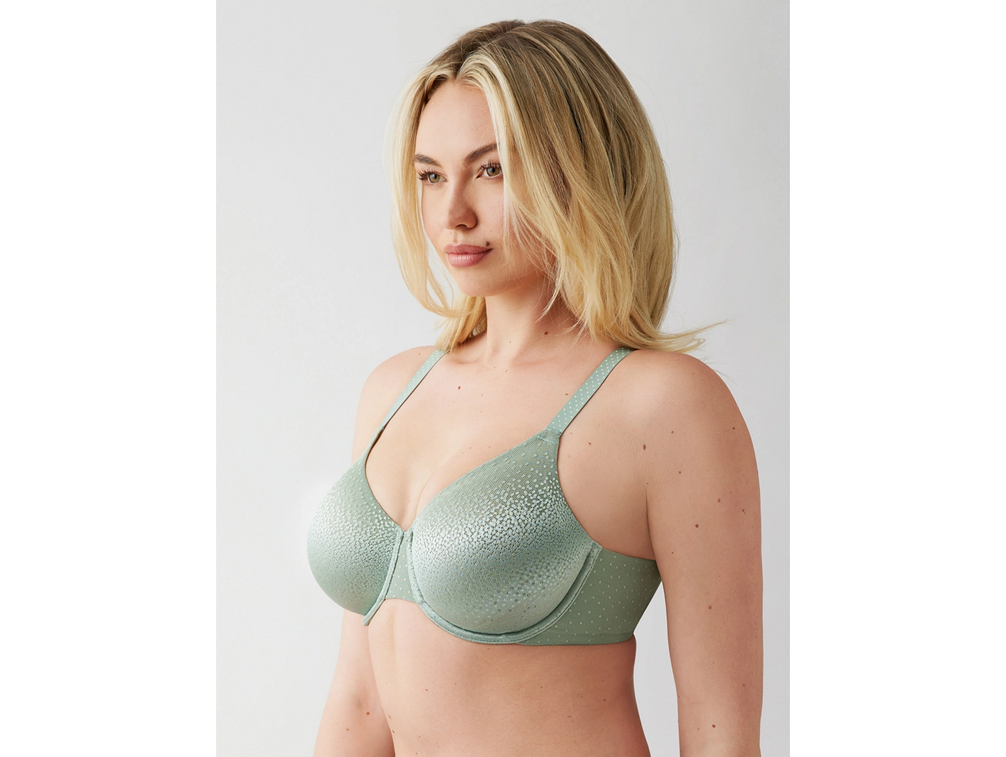 Woman wearing a green bra against a plain background