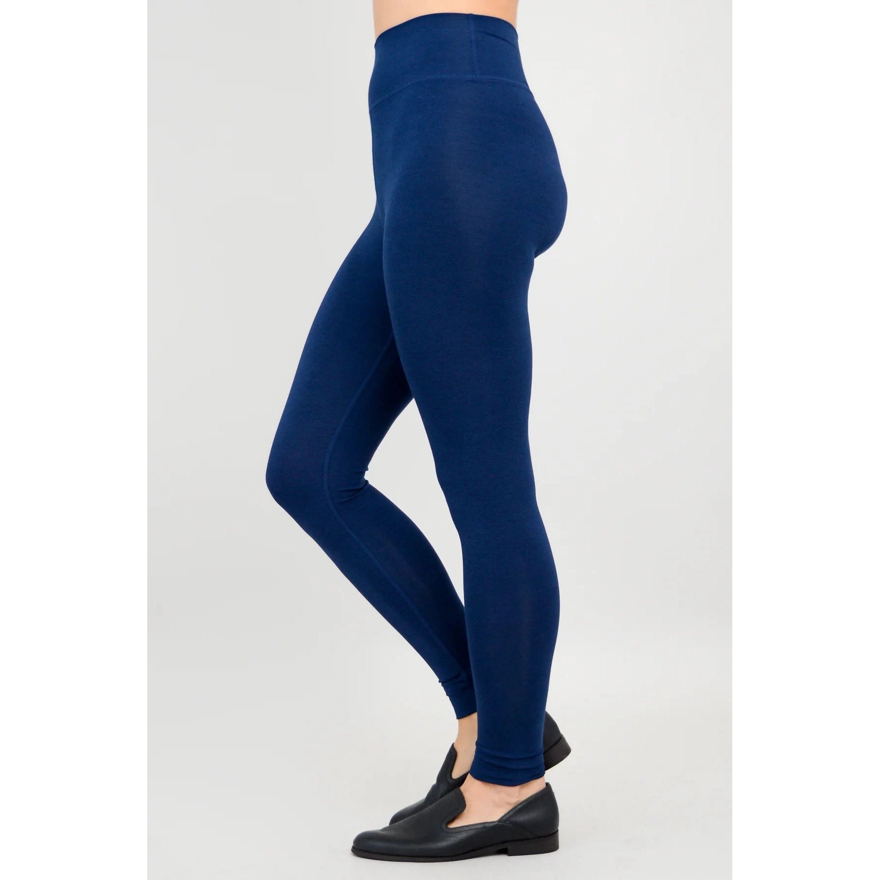 Blue Sky Riley Leggings in Indigo shown on a model against a white background, from the side view.
