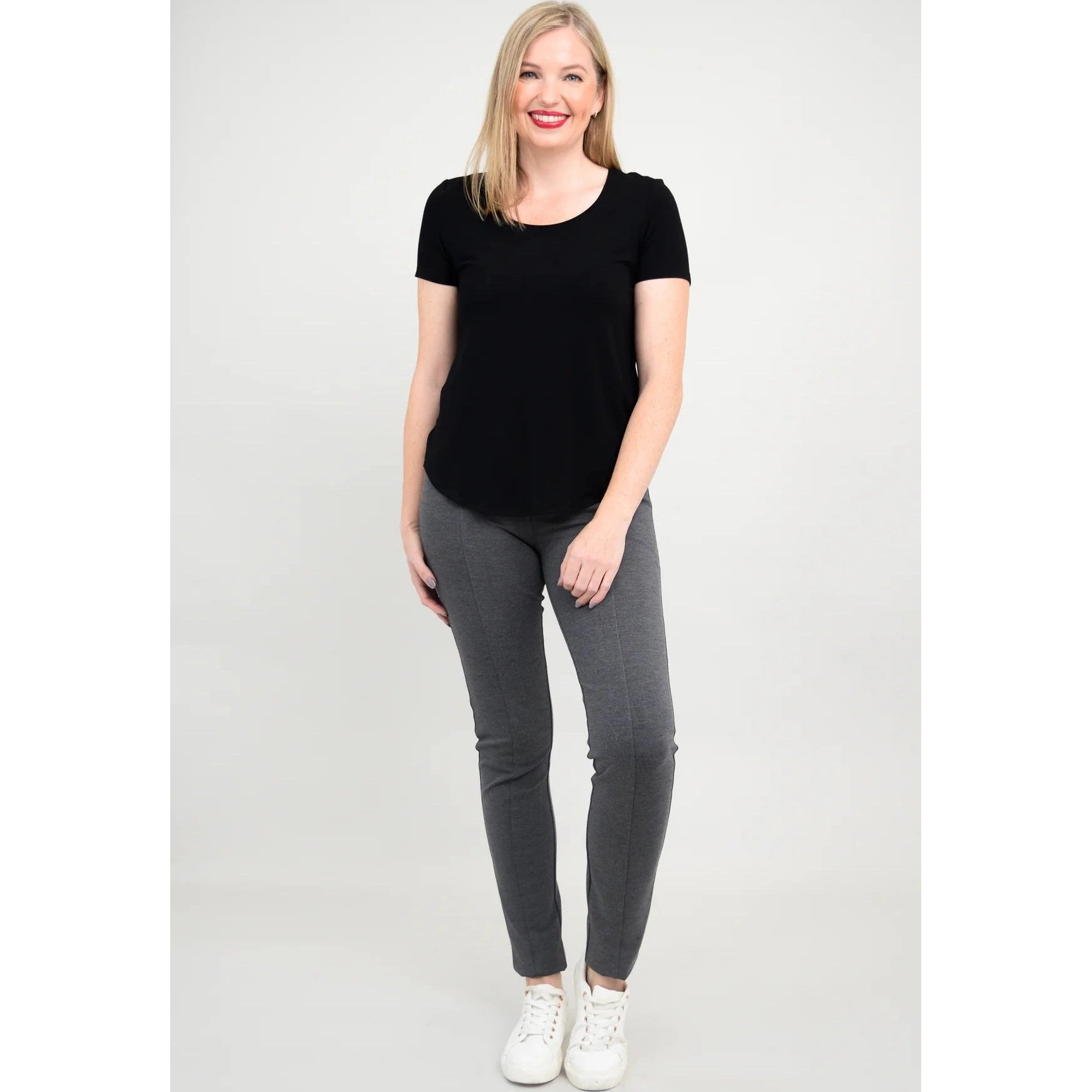 Blue Sky Tessa Tee in Black shown on a model wearing grey leggings standing against a white background, from the front view.