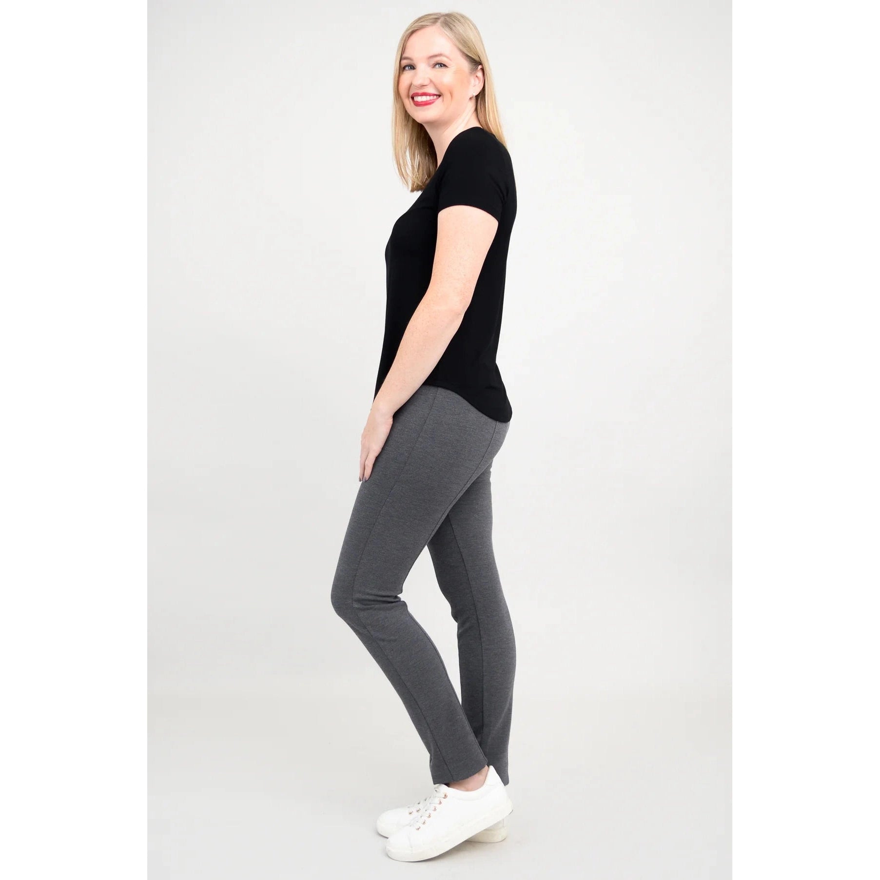 Blue Sky Tessa Tee in Black shown on a model wearing grey leggings standing against a white background, from the side view.
