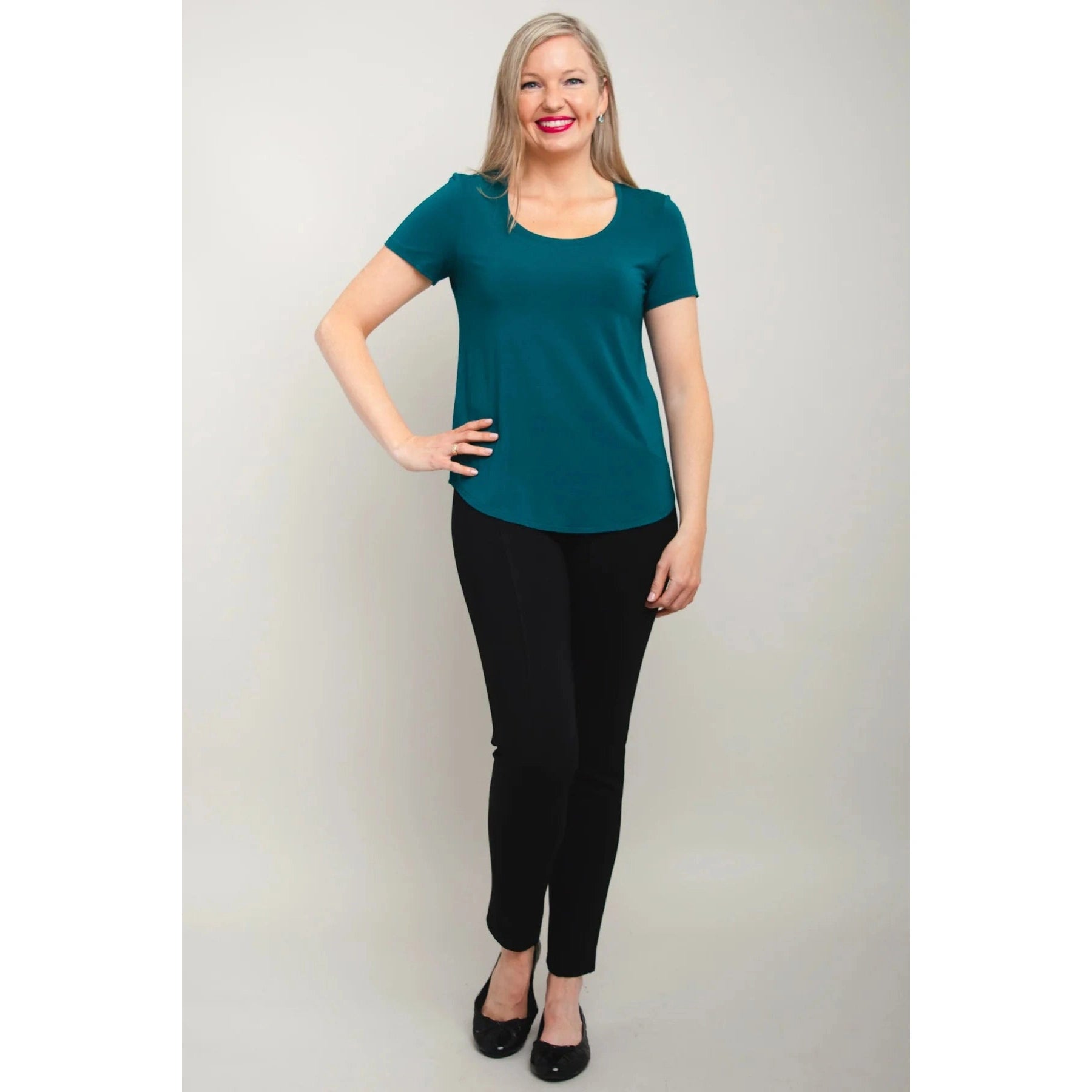 Blue Sky Tessa Tee in Teal shown on a model wearing black leggings against a white background, from the front view.