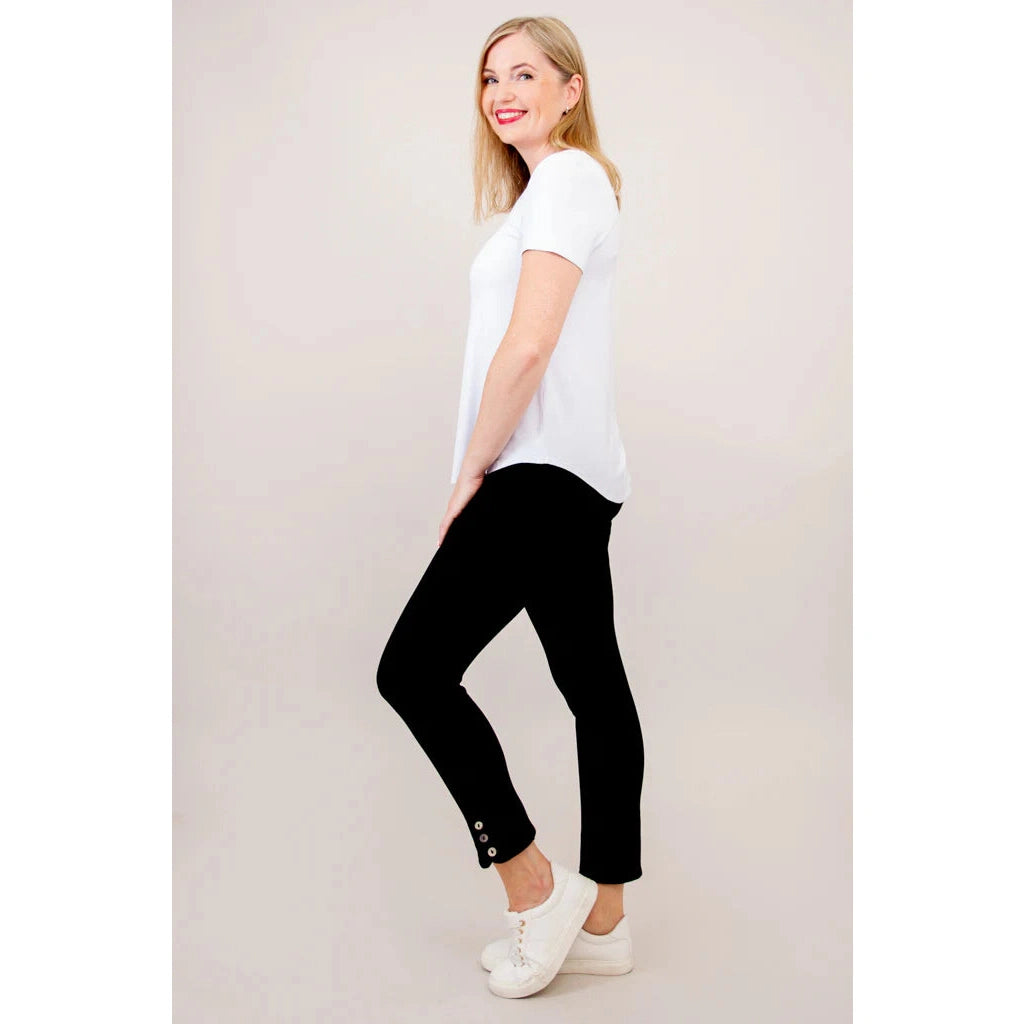 Blue Sky Tessa Tee in white shown on a model wearing black leggings, standing against a white background, from the side view.