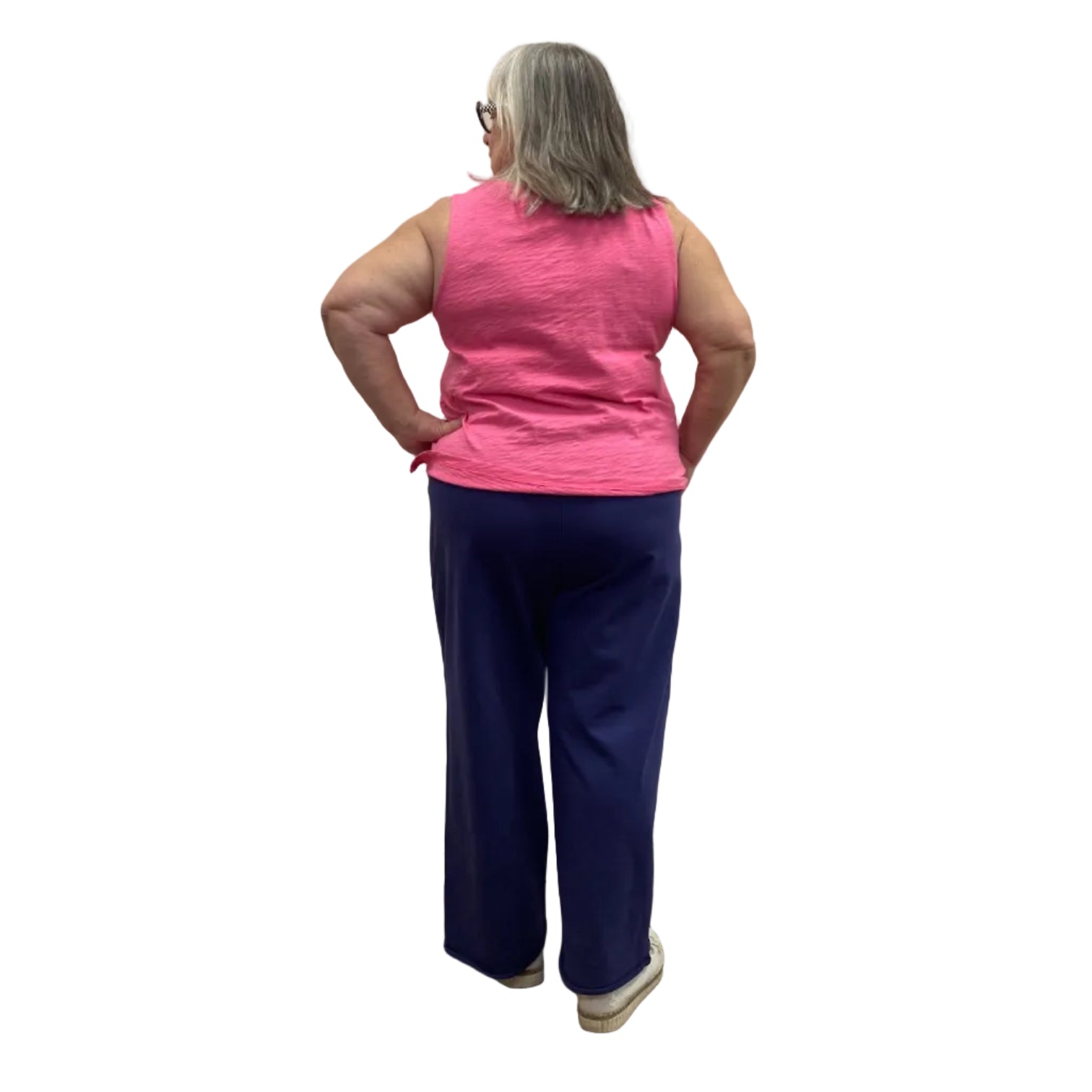 Woman wearing Escape Beach Flood pants in navy with pink tank against white background.