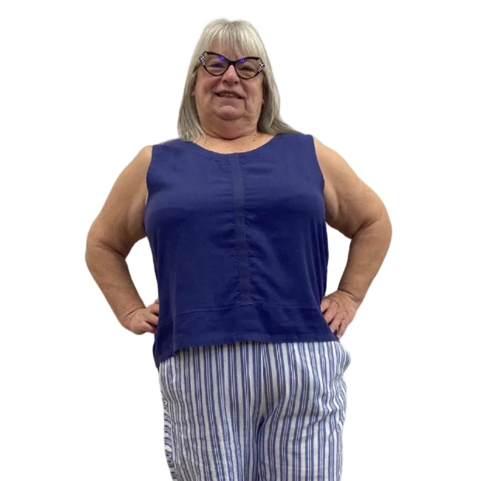 Woman wearing the Escape Getaway Tank in Navy against a white wall, paired with blue and white striped pants.