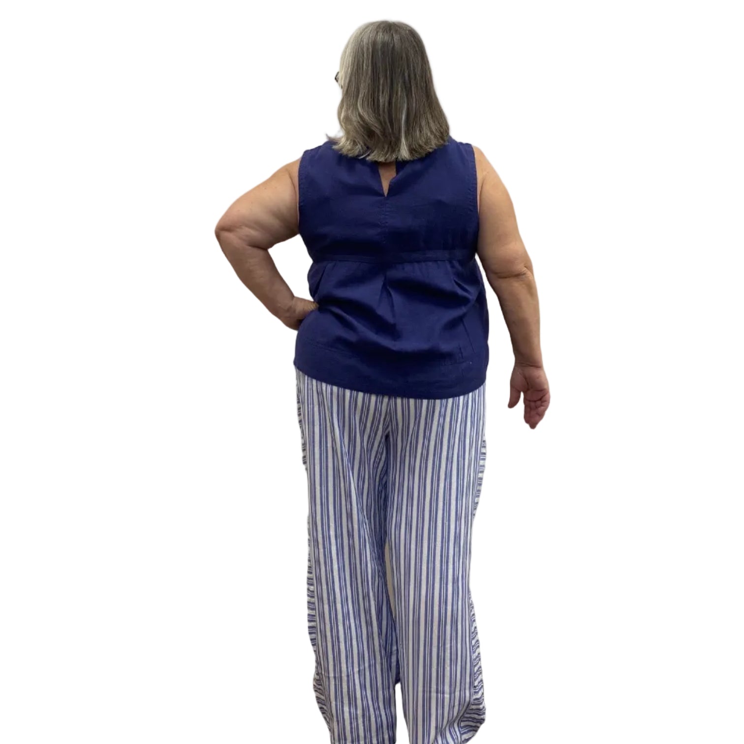 Woman wearing the Escape Getaway Tank in Navy against a white wall, paired with blue and white striped pants.