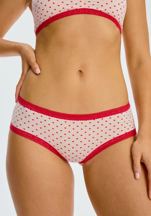 The Micro Hipster Panty in Hearts, which is an ivory low-rise panty with a red heart pattern and red lace trim. 