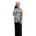 Woman wearing a colorful sleeveless top with abstract patterns on a white background