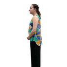 Woman wearing a colorful sleeveless top with black pants on a white background