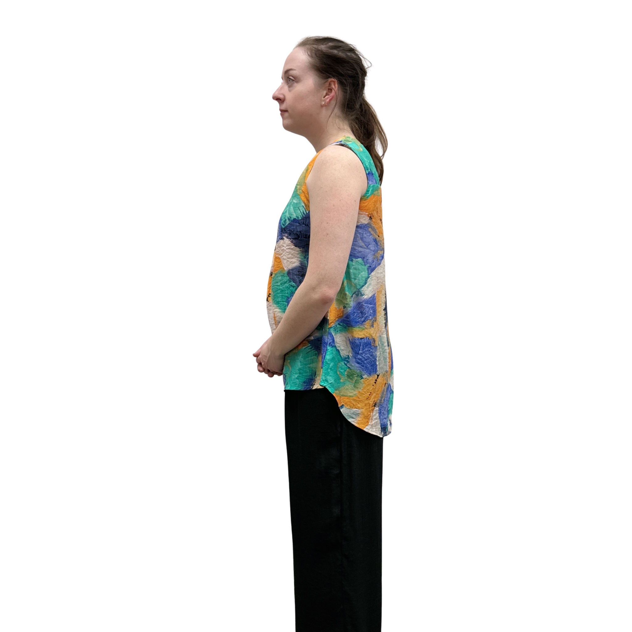 Woman wearing a colorful sleeveless top with black pants on a white background