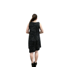 Woman wearing a black sleeveless dress with white patterns on a white background