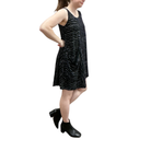 Person wearing a black sleeveless dress with white patterns on a white background