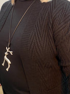 Close-up of a black sweater with a decorative brooch on a plain background