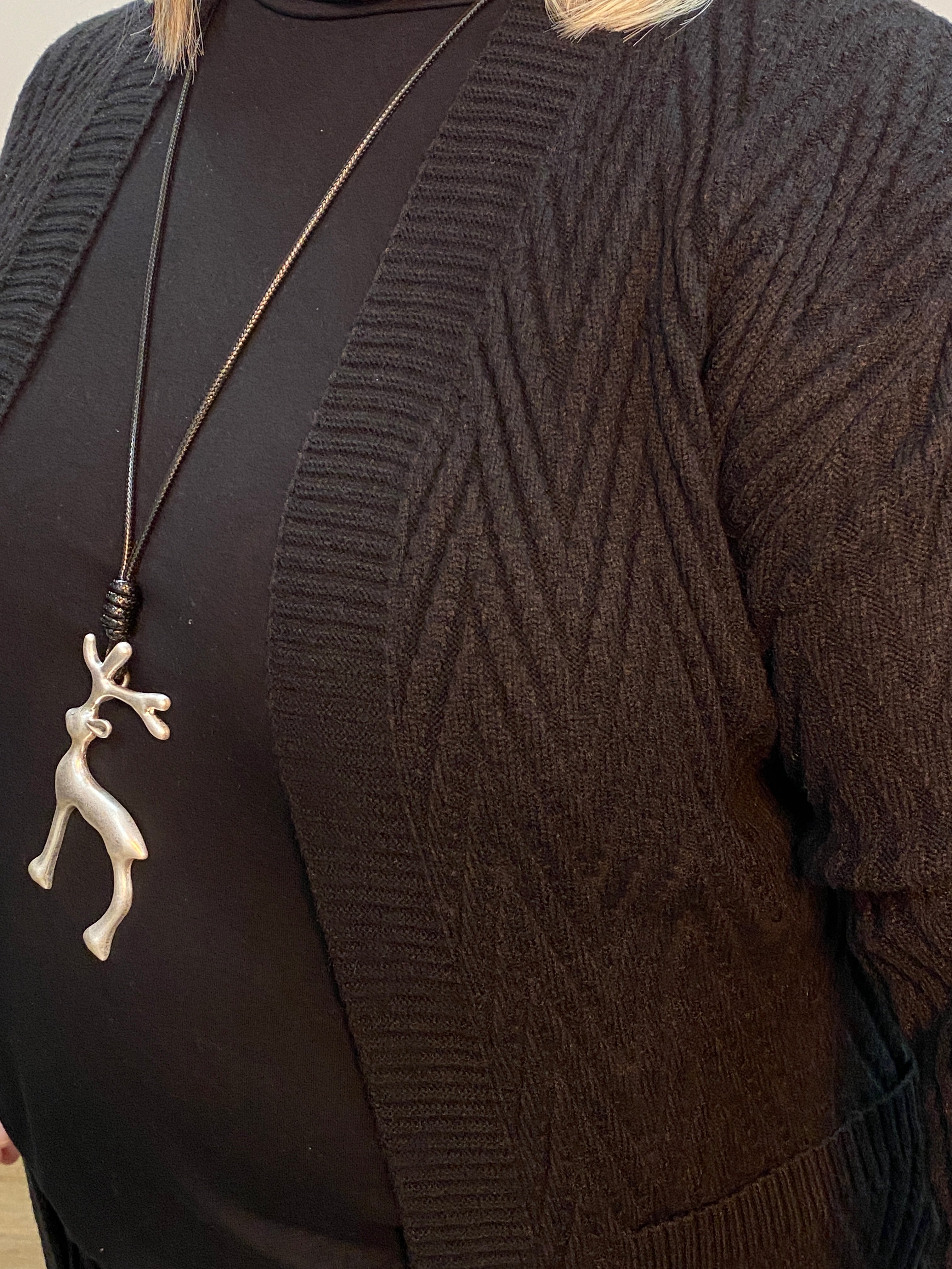 Close-up of a black sweater with a decorative brooch on a plain background