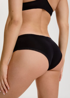 Blush The Micro Hipster in Black shown on model to display the back coverage, shirring, and lace detailing. 