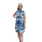 Woman wearing a sleeveless floral dress with blue and white pattern on a white background