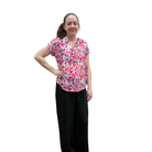 Woman wearing a pink floral blouse and black pants on a white background