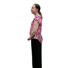 Woman wearing a pink floral shirt and black pants on a white background