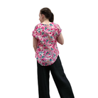 Person wearing a pink floral shirt and black pants on a white background