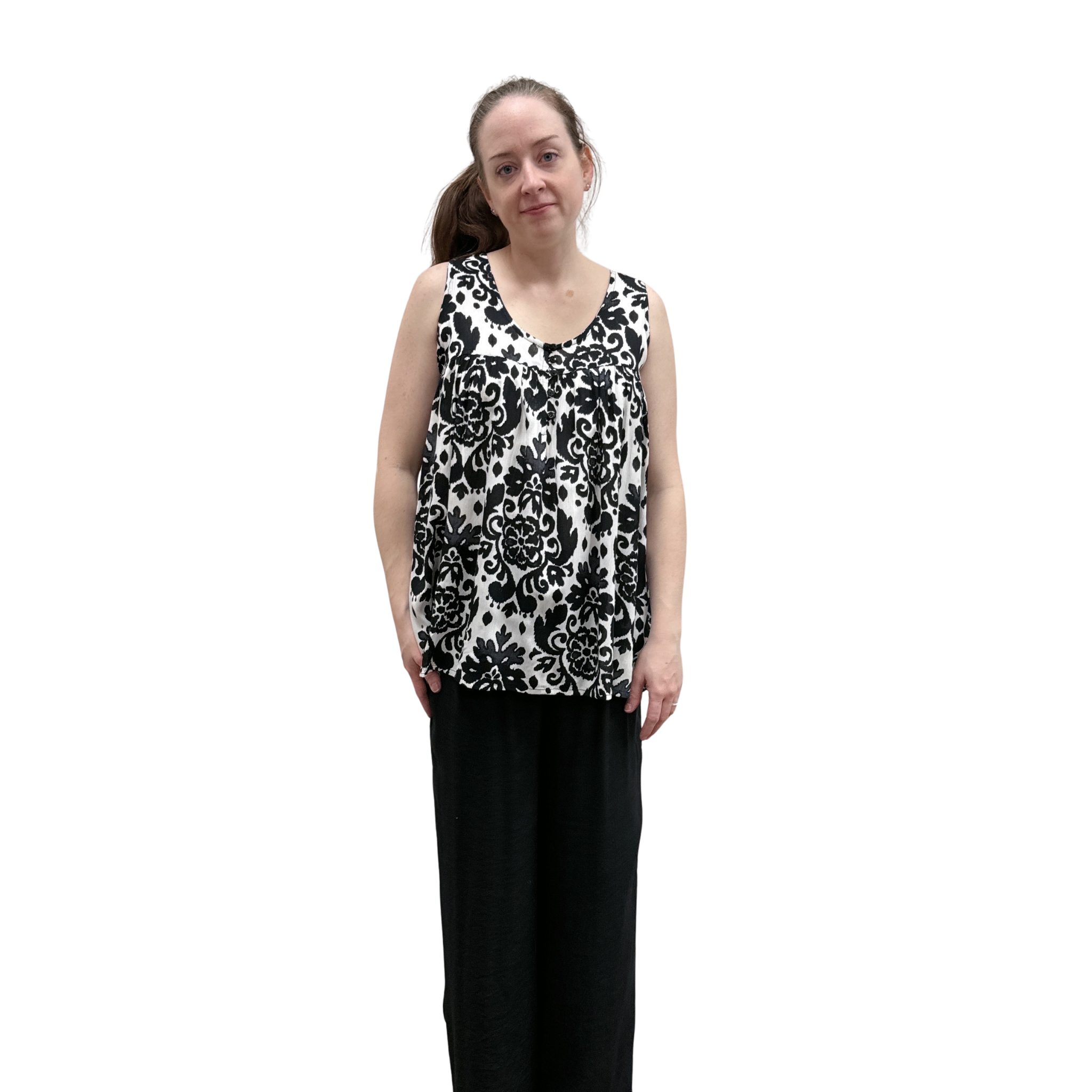 Woman wearing a black and white patterned sleeveless top and black pants on a white background