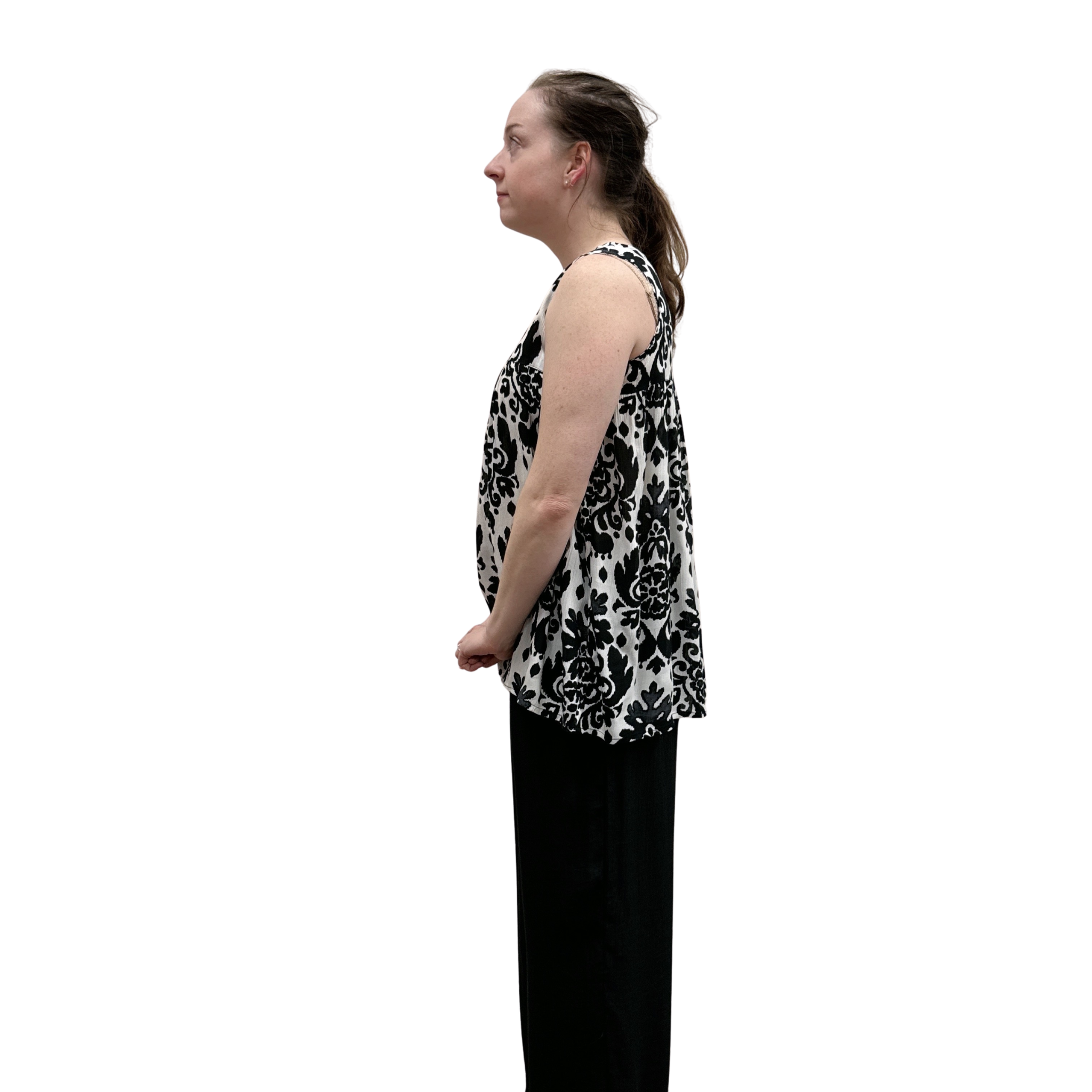 Woman wearing a black and white patterned sleeveless top with black pants on a white background