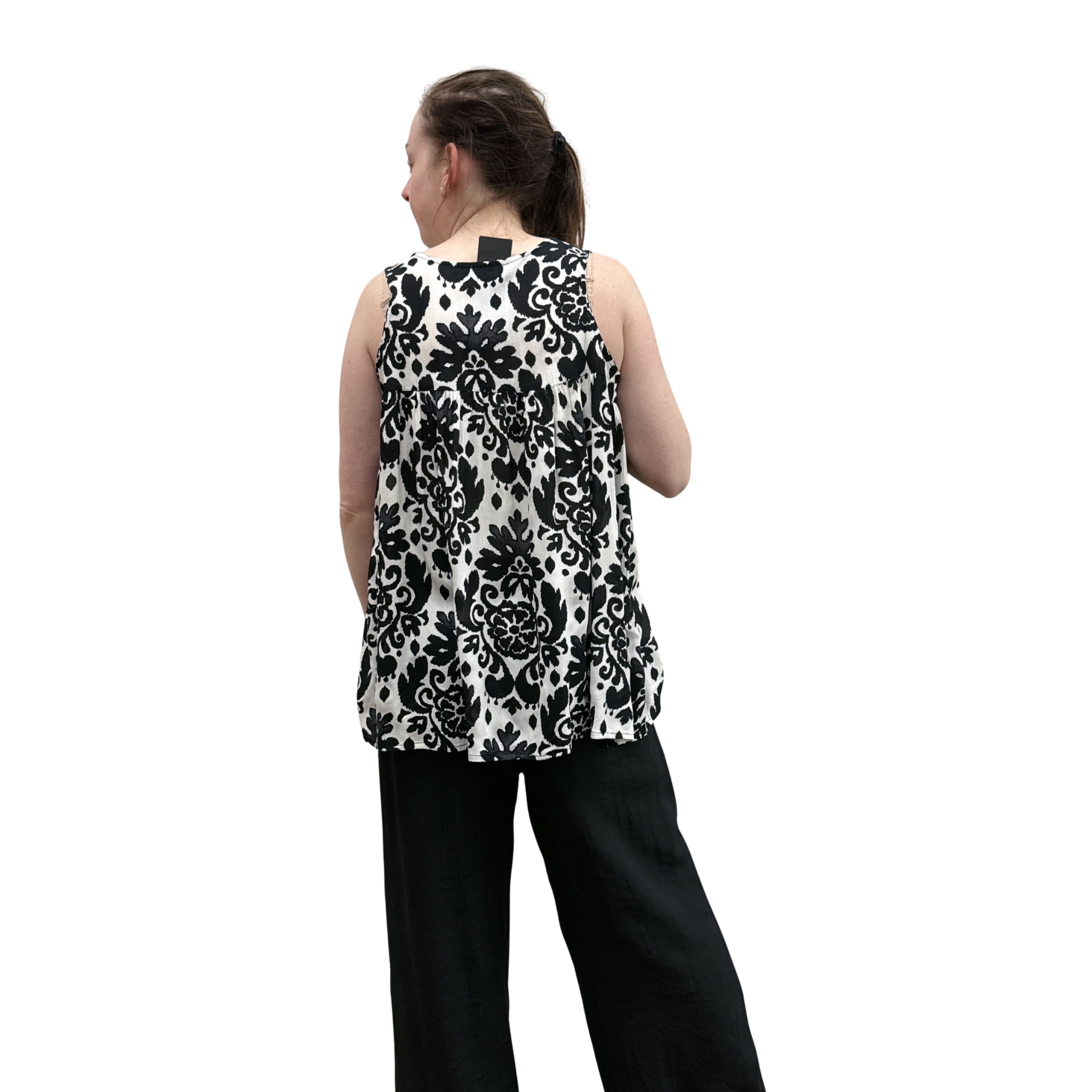 Person wearing a sleeveless black and white floral top on a white background