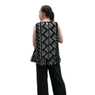 Person wearing a black and white patterned sleeveless top with ruffled layers on a white background